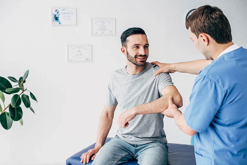 Young woman with raised hands standing on meadow on sunset